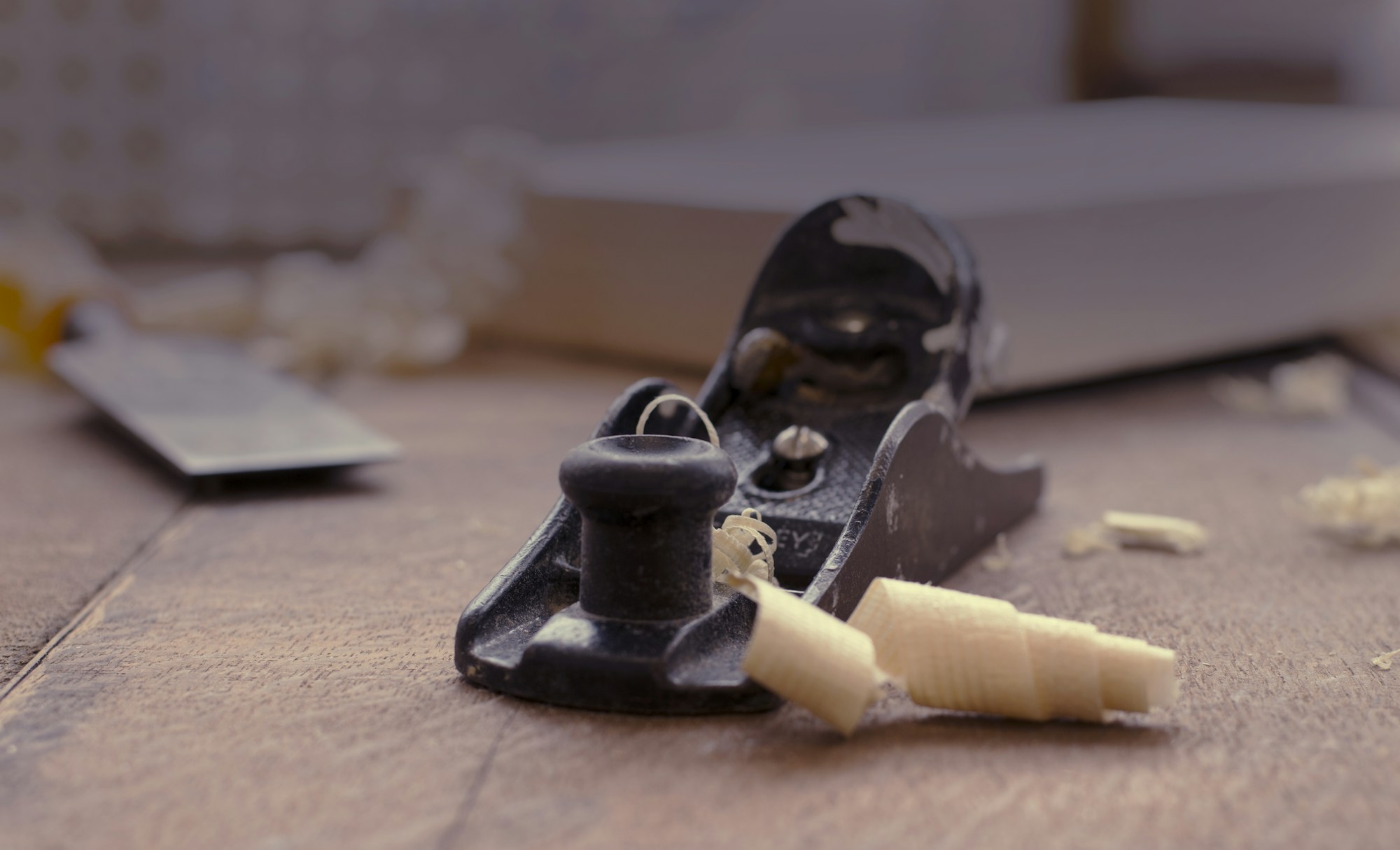A hand plane resting on a board, with a curl of shaving