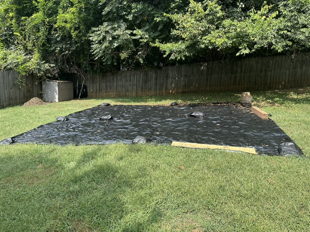 The whole plot under a black tarp held down with sandbags